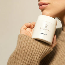 Load image into Gallery viewer, A close-up of a person holding a white jar of Danucera Cerabalm against a neutral beige background.
