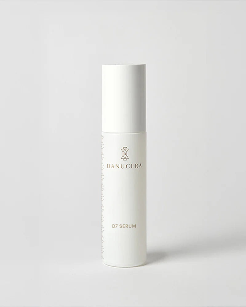 A white cylindrical cosmetic bottle labeled 'DANUCERA 07 SERUM' on a clean light gray background.